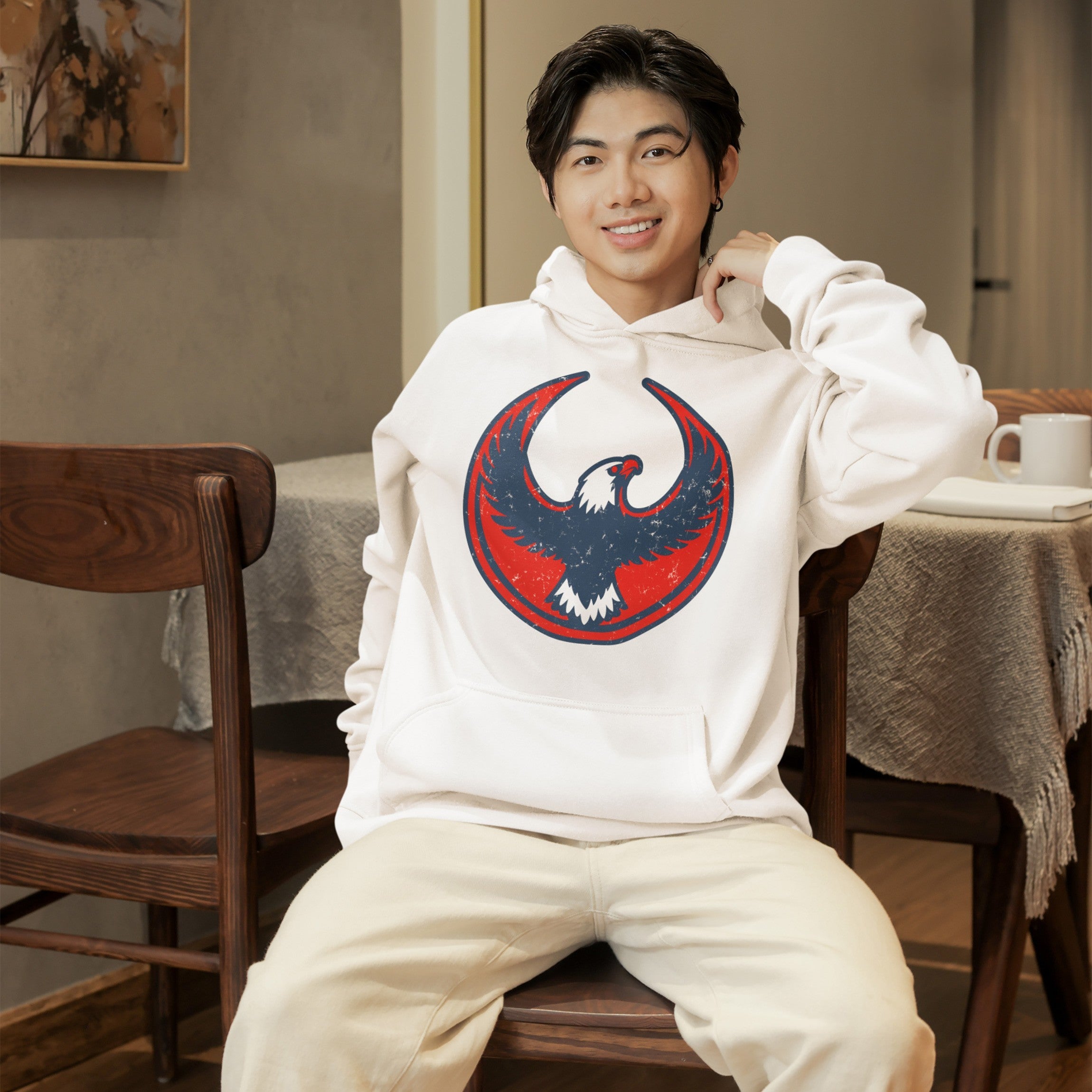 Young person wearing USA Rebel Alliance Hoodie, featuring a red and dark blue eagle emblem, sitting casually in a dining setting with a smile, embodying a patriotic and defiant spirit.