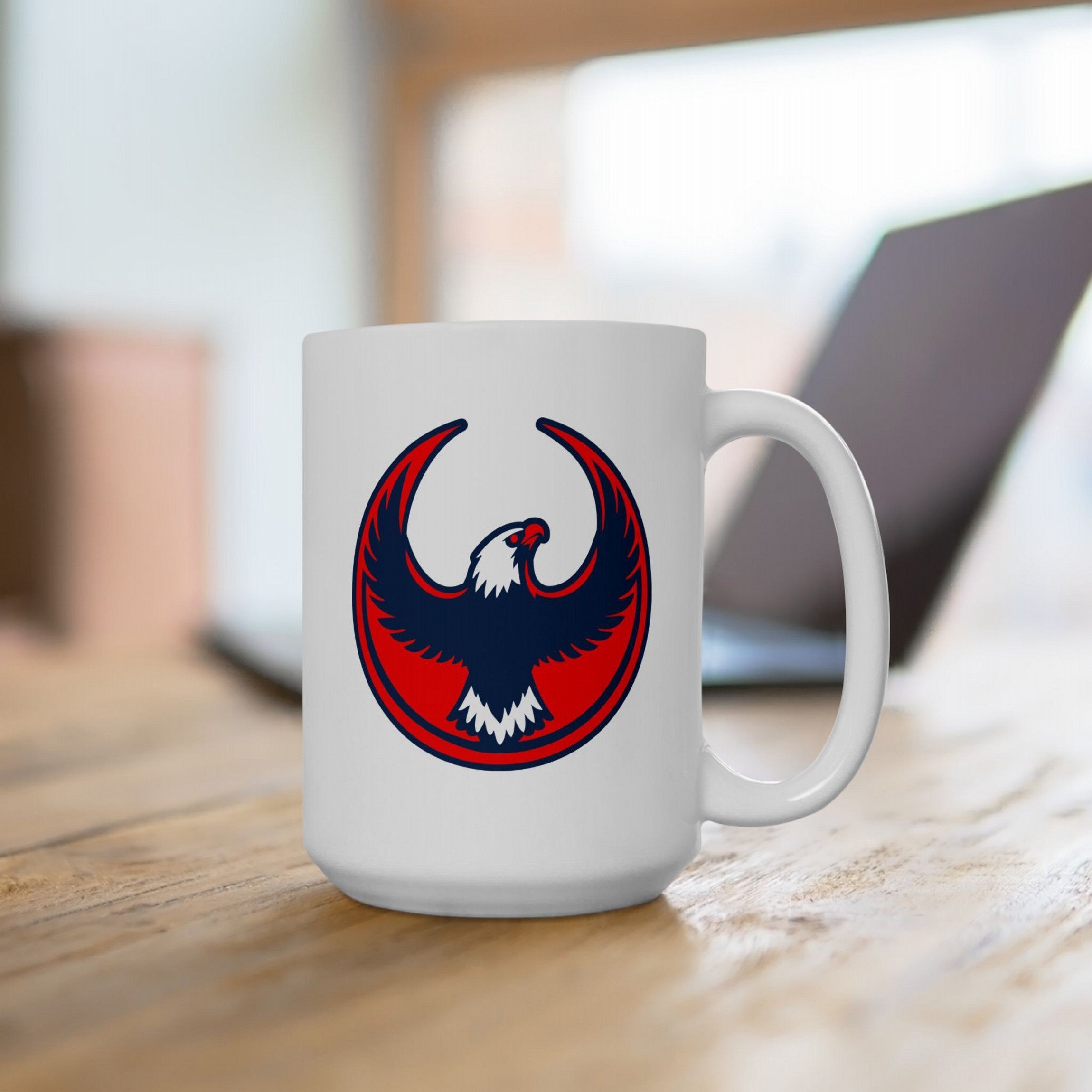USA Rebel Alliance Mug on a wooden desk, featuring a bold eagle emblem in red, navy, and white. It's positioned before a laptop, symbolizing activism and patriotism in a home-office setting.