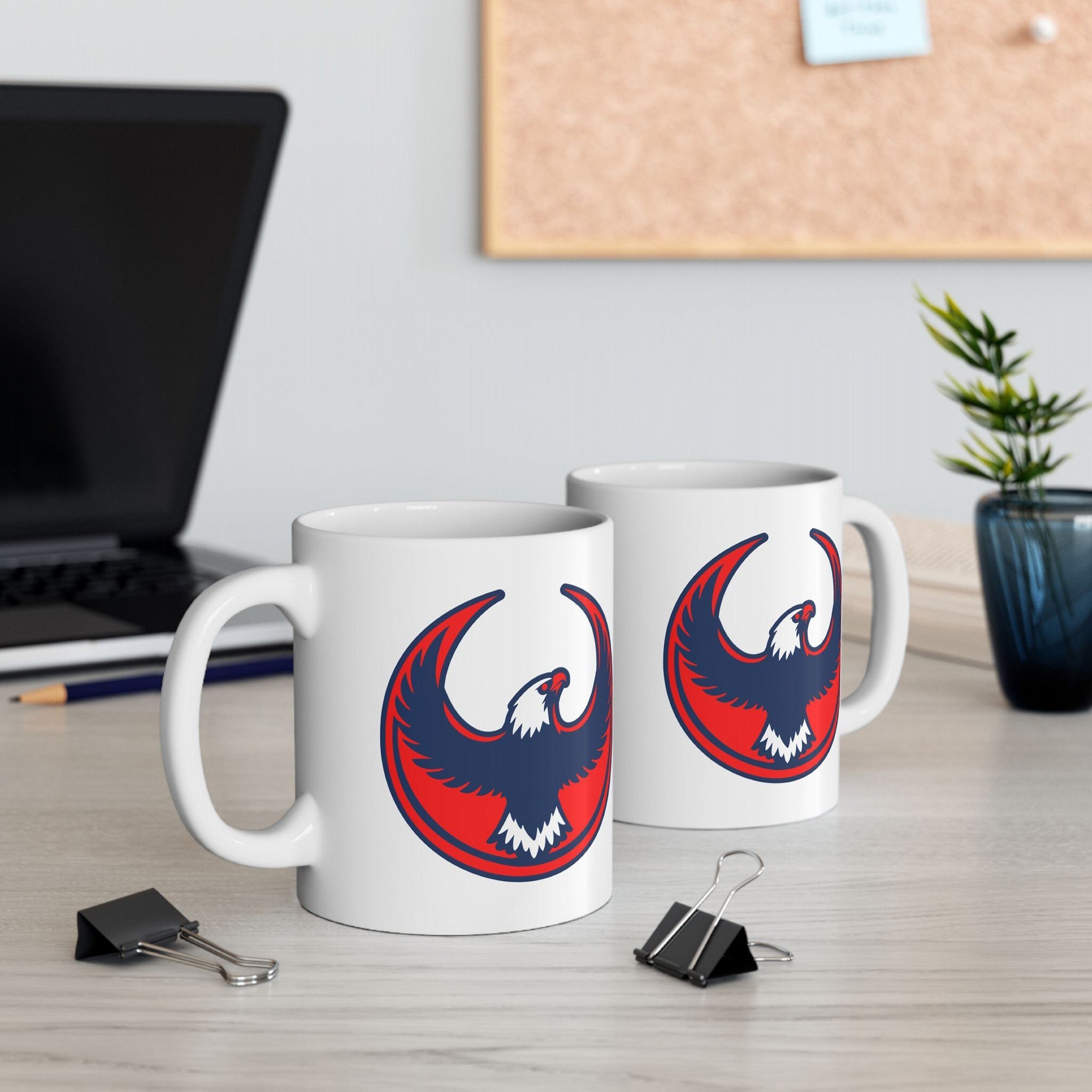 USA Rebel Alliance Mug featuring a red and navy stylized eagle logo on a white ceramic surface, positioned on a light-wood desk with a workspace backdrop, embodying anti-fascist and patriotic themes.