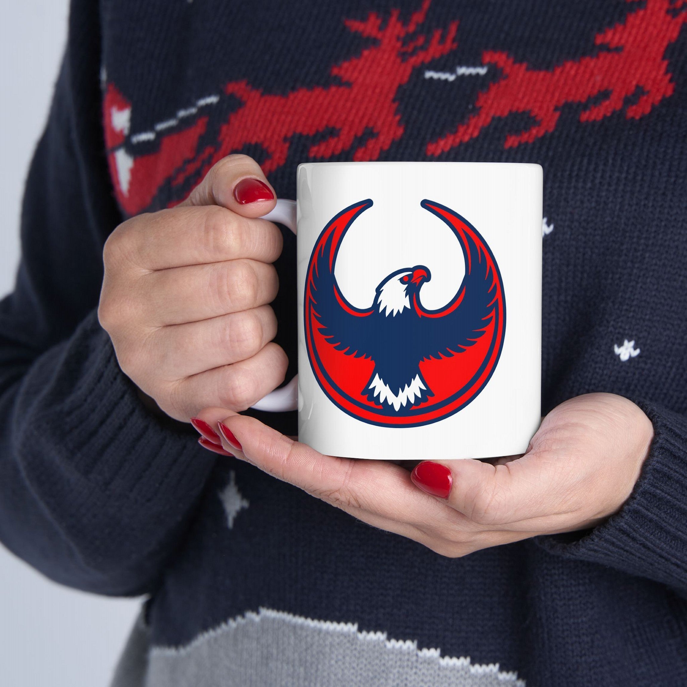Person holding the USA Rebel Alliance Mug, featuring a bold red and navy stylized eagle emblem. The design symbolizes anti-fascist values, aligning with immigrant rights and community defense.