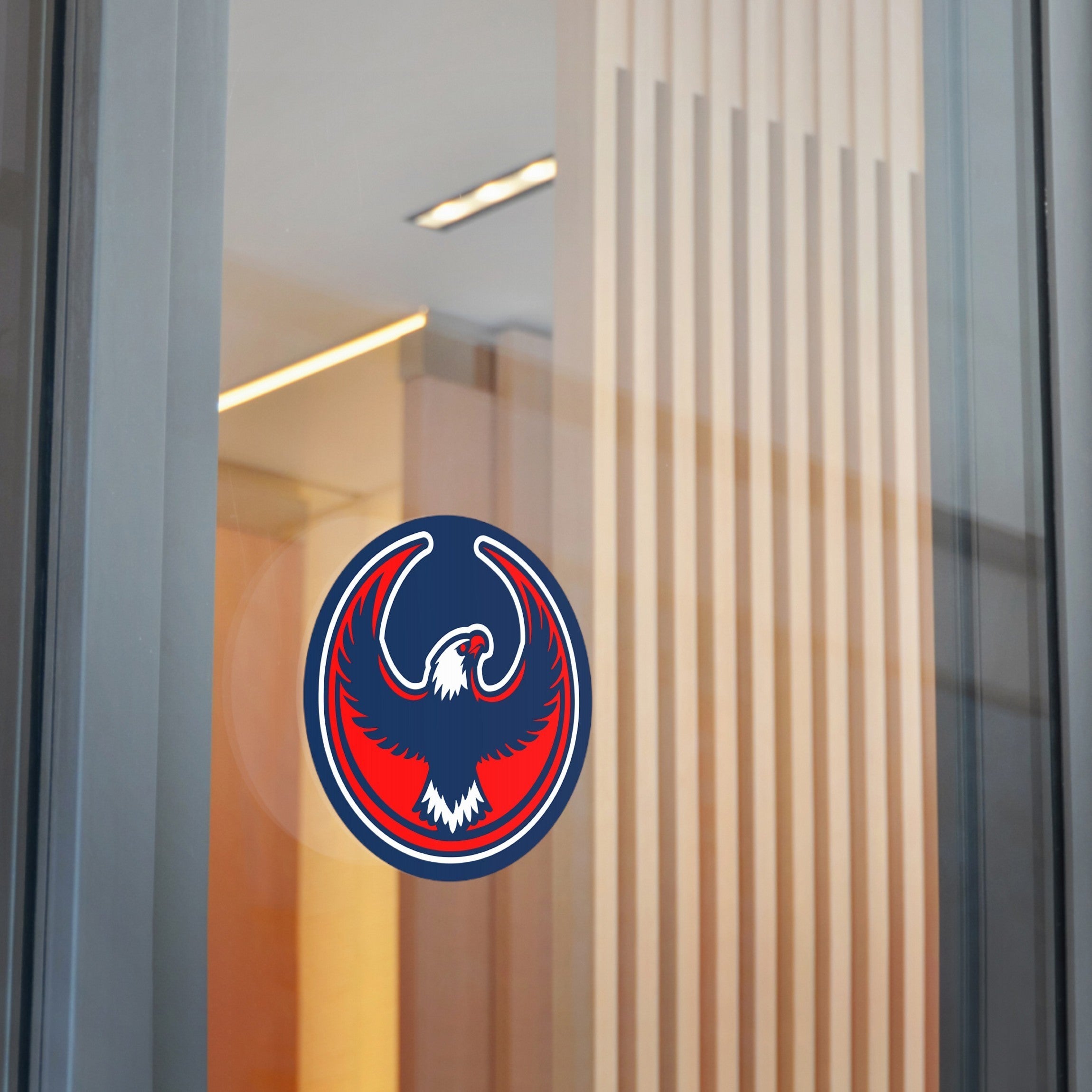 USA Rebel Alliance Sticker displayed on a glass partition, featuring a stylized eagle with raised wings in a circular formation, symbolizing activism and patriotism in red, white, and navy colors.