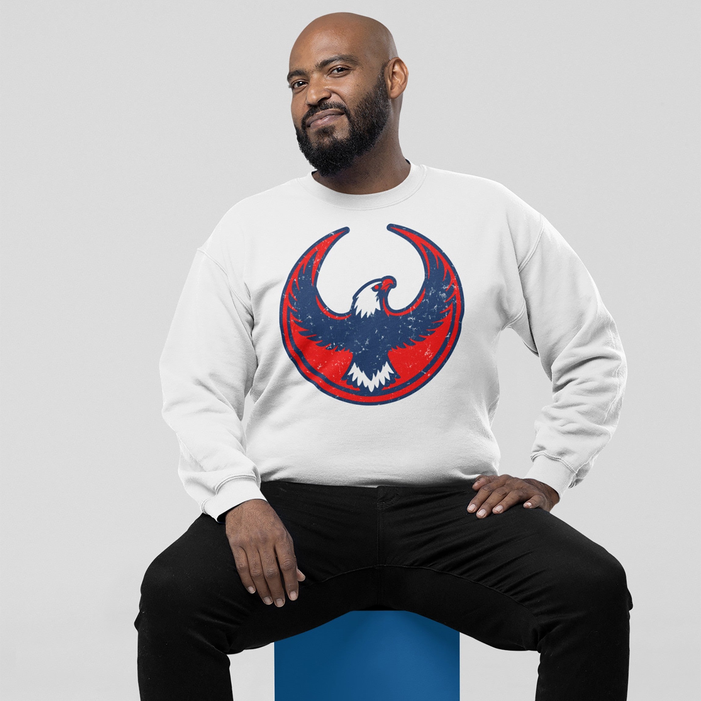 USA Rebel Alliance Hoodie & Sweatshirt showcases a bearded man wearing a white crew-neck sweatshirt adorned with a red and blue distressed eagle emblem, symbolizing defiance and patriotism.