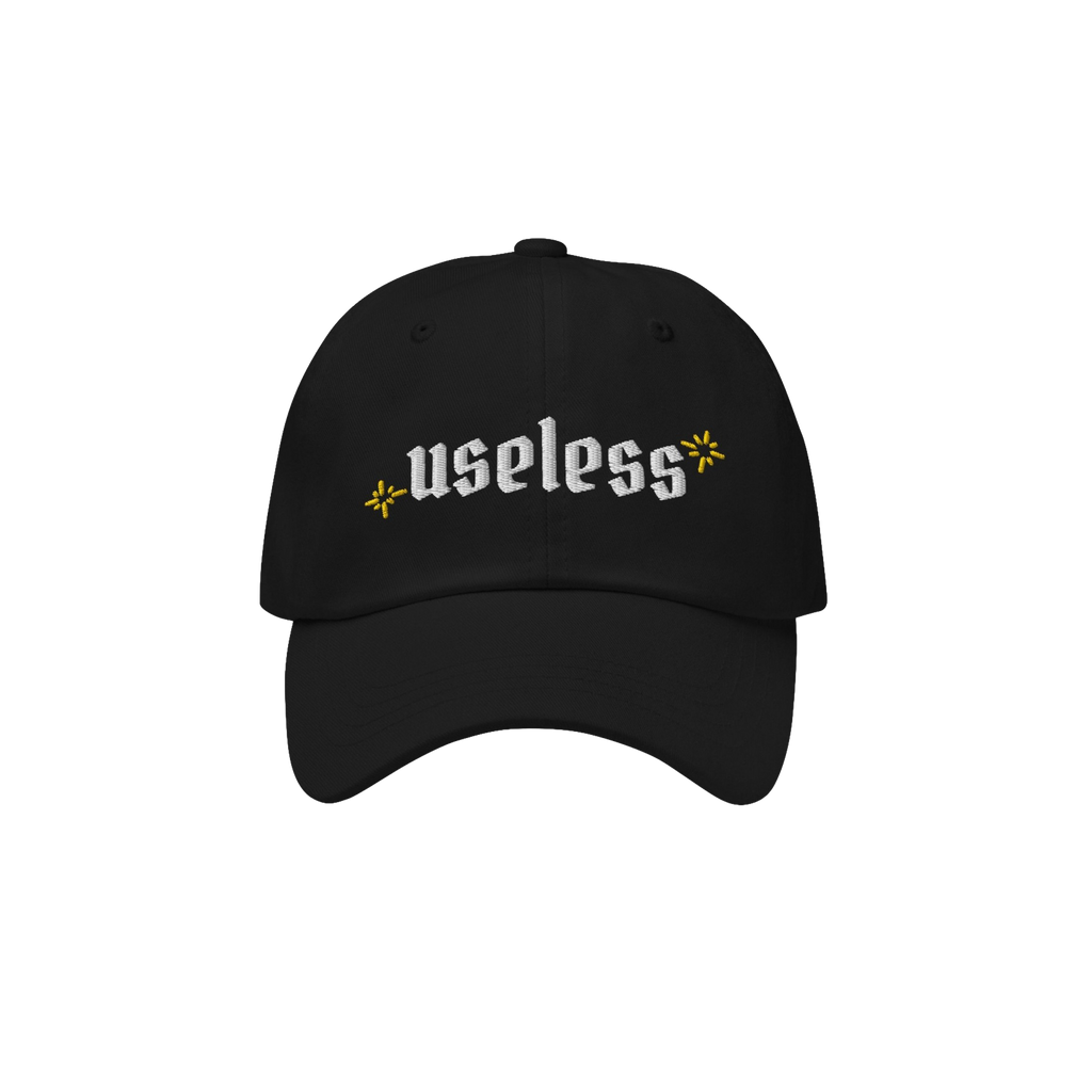 Black Useless Hat with “useless” in white embroidery and yellow star accents, symbolizing rest and reflection. Available 