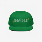 Useless Hat: A green baseball cap with useless in white Old English embroidery, flanked by yellow starbursts, promoting restful rebellion and unapologetic chill, aligning with supportive, inclusive values.