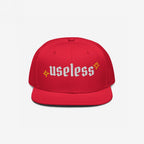 Useless Hat: A red snapback cap with useless in white Old English font, flanked by yellow starbursts, promoting relaxation and self-care with a bold, unapologetic statement.
