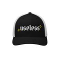 The Useless Hat, a two-tone trucker cap, features useless in bold Old English font on black fabric, flanked by yellow starbur