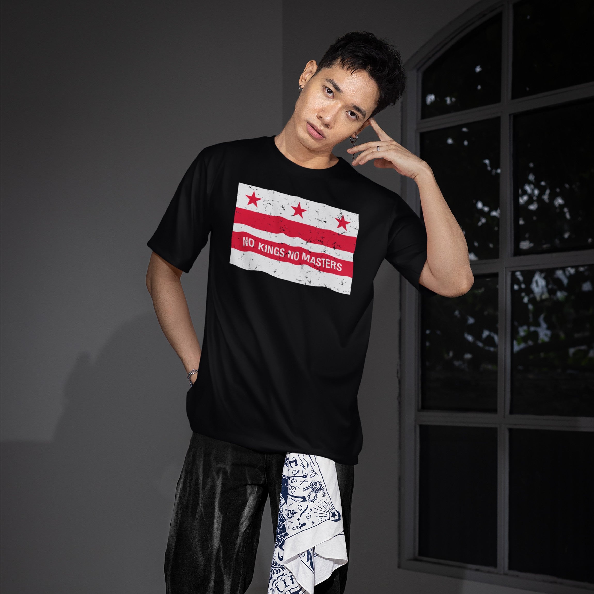 Young man wearing Washington DC No Kings Flag Shirt with distressed graphic of red stars and stripes, slogan NO KINGS NO MASTERS in white, embodying a bold anti-authoritarian statement.