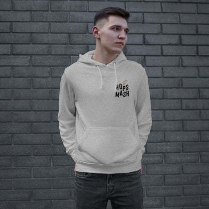 Young man wearing the Wasted Days Hoodie, featuring a subtle “HOPS MASH” logo on the chest, embodies an urban vibe against a brick wall, hands in the kangaroo pocket, looking contemplative.