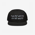 The Wasted Days Hat features bold white embroidery stating, A Day Not Wasted Is A Day Wasted, on a black snapback, embodying a carefree, unapologetic lifestyle ideal for vibrant, inclusive gatherings.