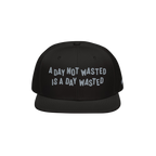 The Wasted Days Hat features bold white embroidery stating, A Day Not Wasted Is A Day Wasted, on a black snapback, embodying 