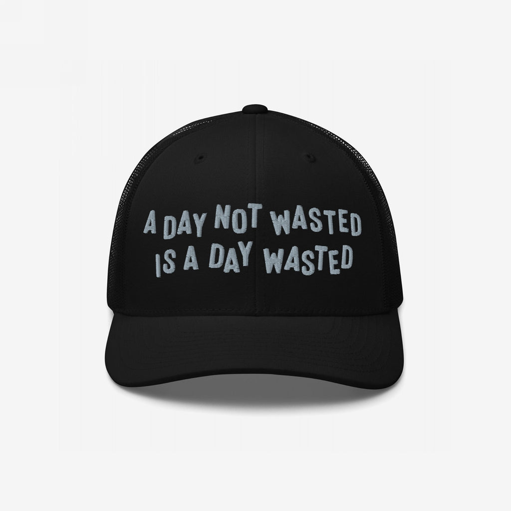 Wasted Days Hat featuring the phrase A Day Not Wasted Is A Day Wasted embroidered in a playful font on a black mesh-back trucker hat, embodying a carefree, bold lifestyle statement.