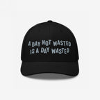Wasted Days Hat featuring the phrase A Day Not Wasted Is A Day Wasted embroidered in a playful font on a black mesh-back trucker hat, embodying a carefree, bold lifestyle statement.