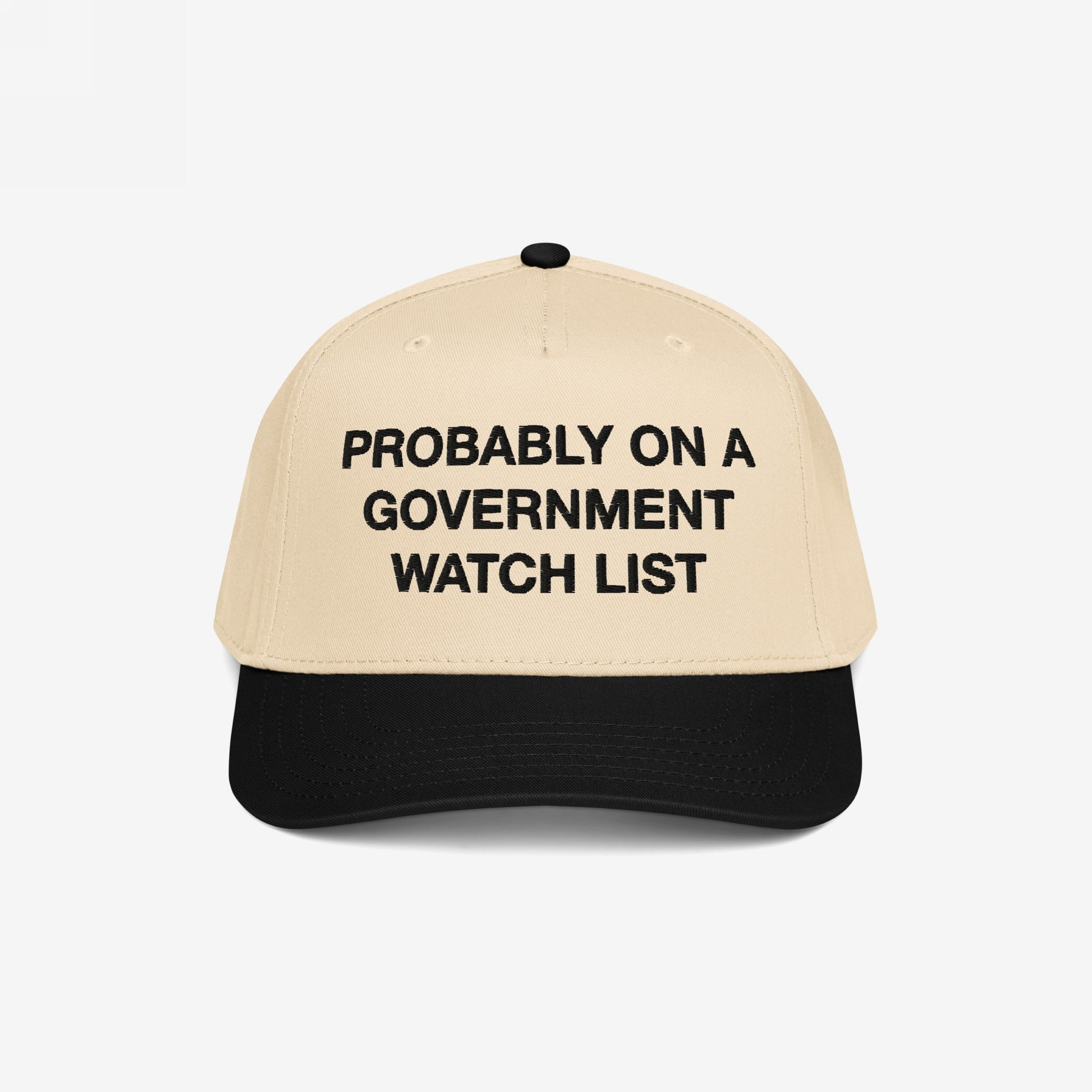 The Watch List Hat features a beige crown with a black brim. Bold black letters declare, PROBABLY ON A GOVERNMENT WATCH LIST, embodying a bold statement on visibility and resistance.