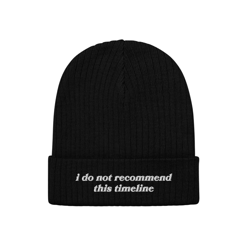 The Watch List Hat is a black rib-knit beanie with a folded cuff, featuring the bold white slogan “PROBABLY ON A GOVERNMENT