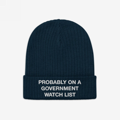 Dark blue Watch List Hat with a folded cuff featuring the embroidered phrase “PROBABLY ON A GOVERNMENT WATCH LIST” in white, embodying bold protest and advocacy through fashion.