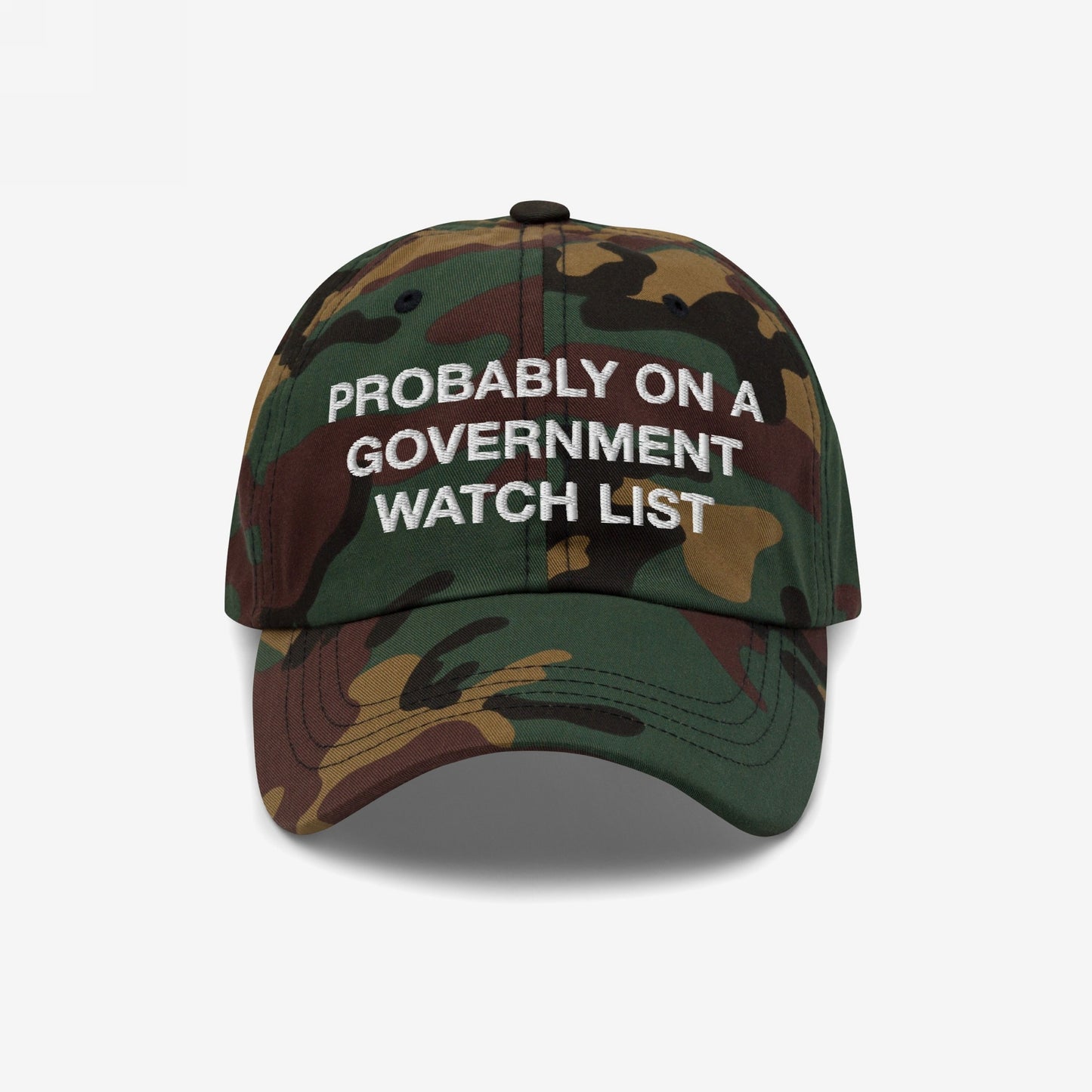 Watch List Hat: Six-panel baseball cap in woodland camo with “PROBABLY ON A GOVERNMENT WATCH LIST” stitched in white, featuring a curved brim, embodying a bold, protest-driven statement.