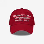 Watch List Hat featuring bold white embroidery with the phrase Probably on a Government Watch List, on a bright red baseball cap, symbolizing defiance and political awareness.