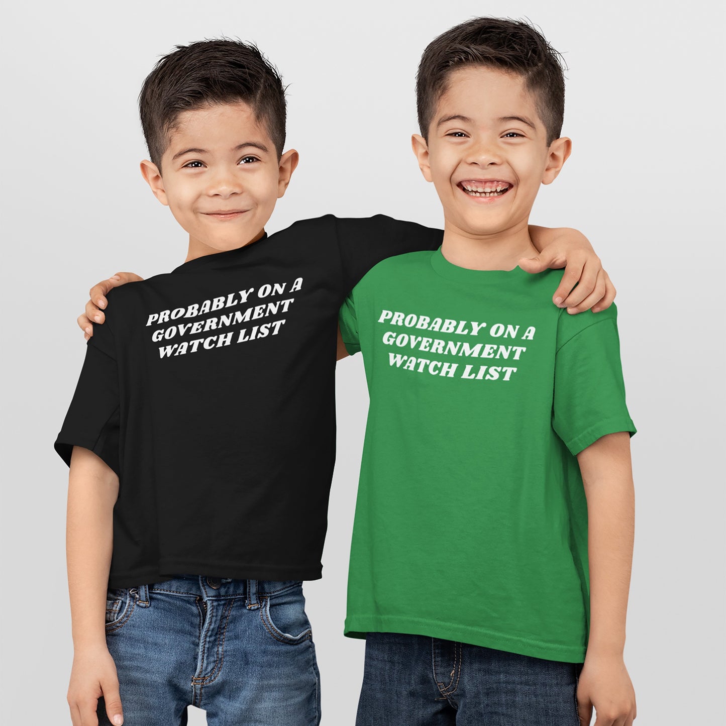 Two young boys embrace, wearing Watch List T-shirts with PROBABLY ON A GOVERNMENT WATCH LIST slogan, embodying defiant spirit and visibility, aligned with the store’s advocacy for equality and justice.