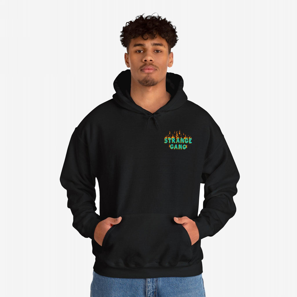 A black hoodie featuring Your Favorite Band Has Always Been Political with green lettering and orange flames, worn by a male model with blue jeans, hands in the front pouch pocket.