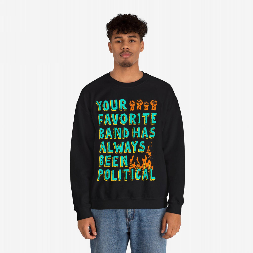 Young man in a black Your Favorite Band Has Always Been Political sweatshirt with colorful lettering, raised fists, and flame graphic. Perfect for fans of politically charged music.